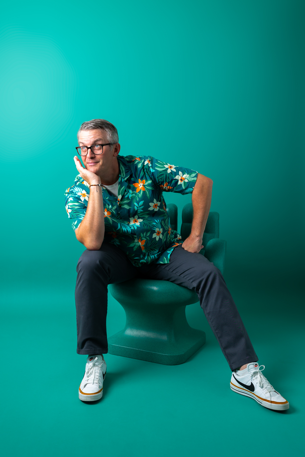 Justin Guardiani seated in a modern lime green armchair, wearing a blue chambray shirt and khakis